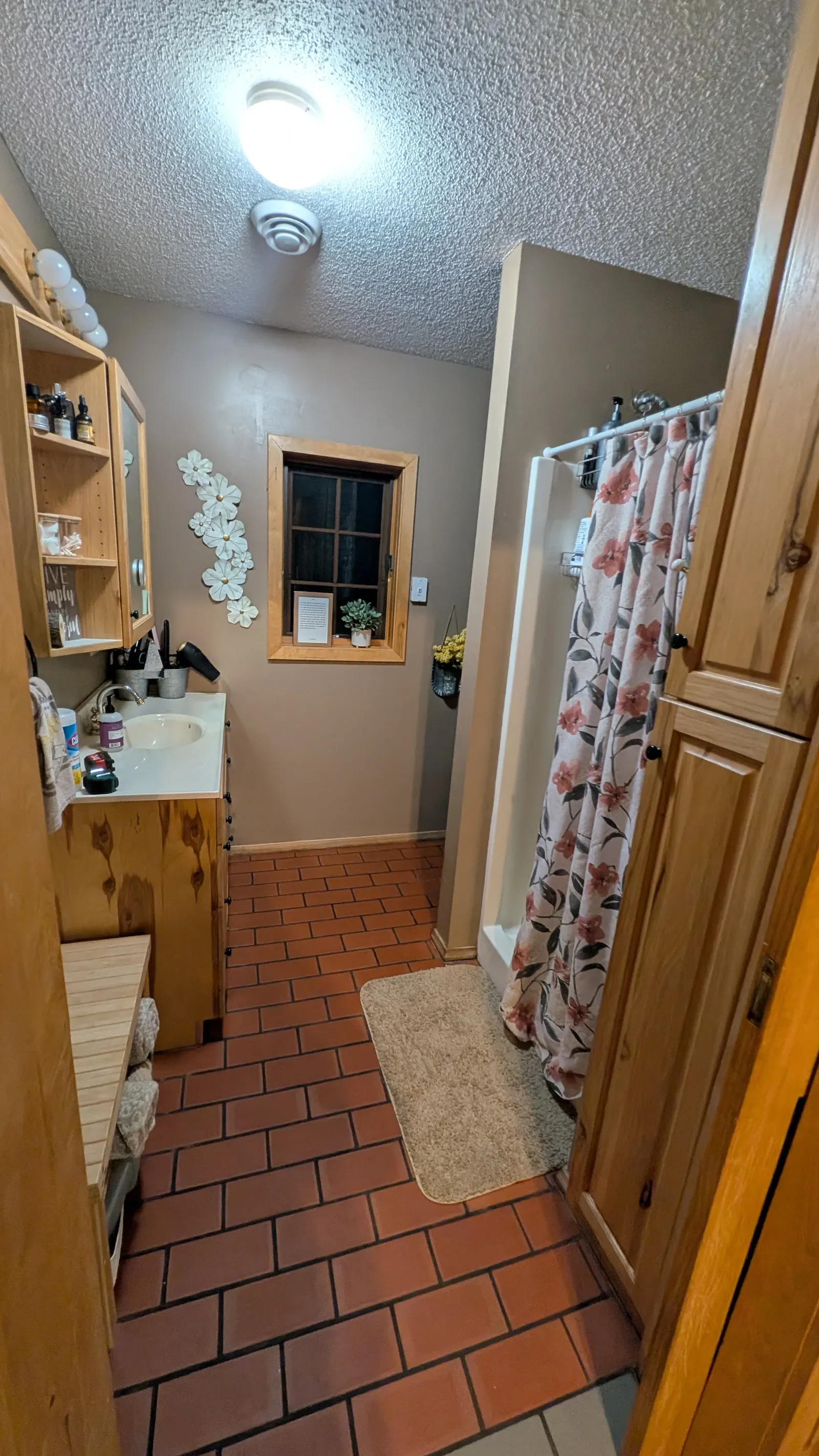 Bathroom before showing brick tile floor, pine cabinet, and full layout