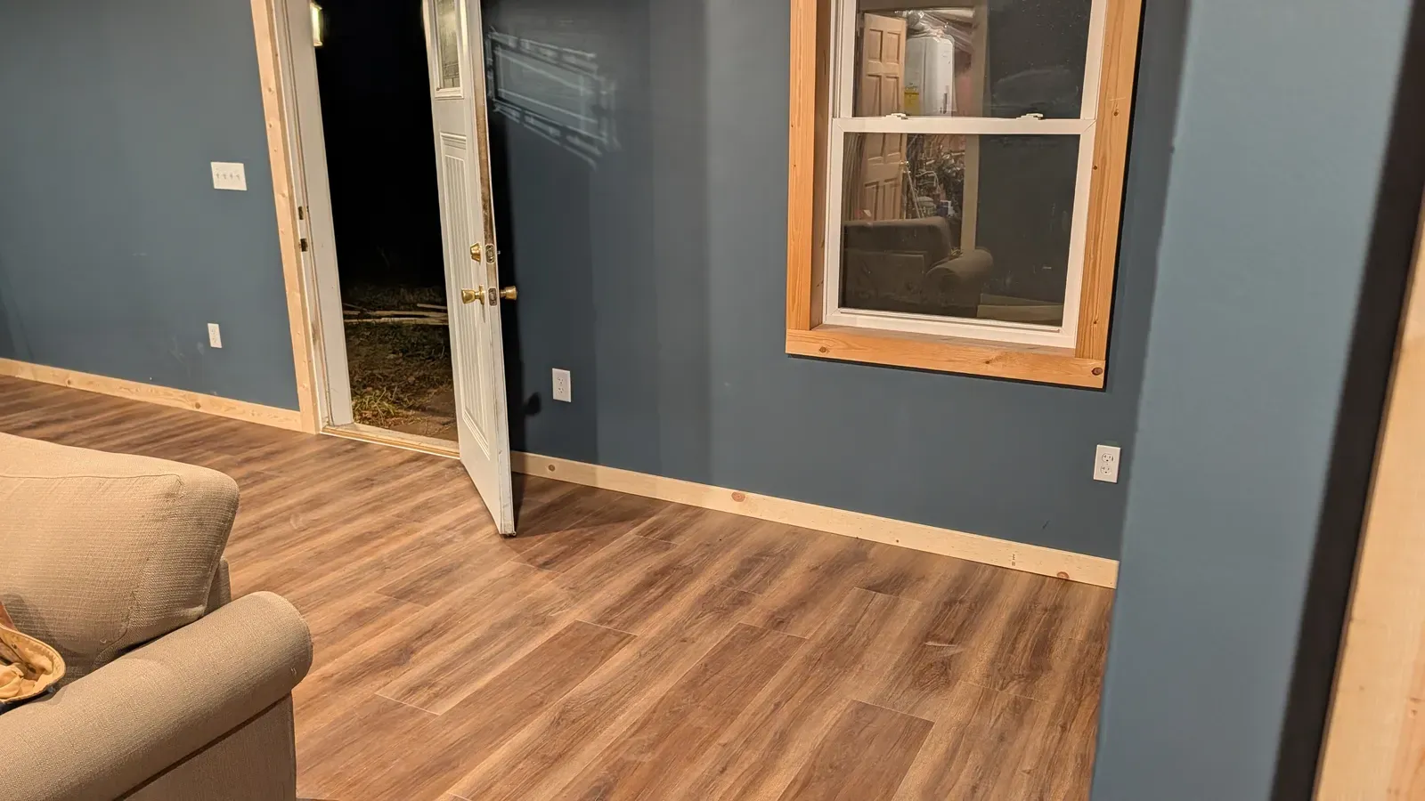 Living area with new LVP flooring, blue painted walls, and pine trim details