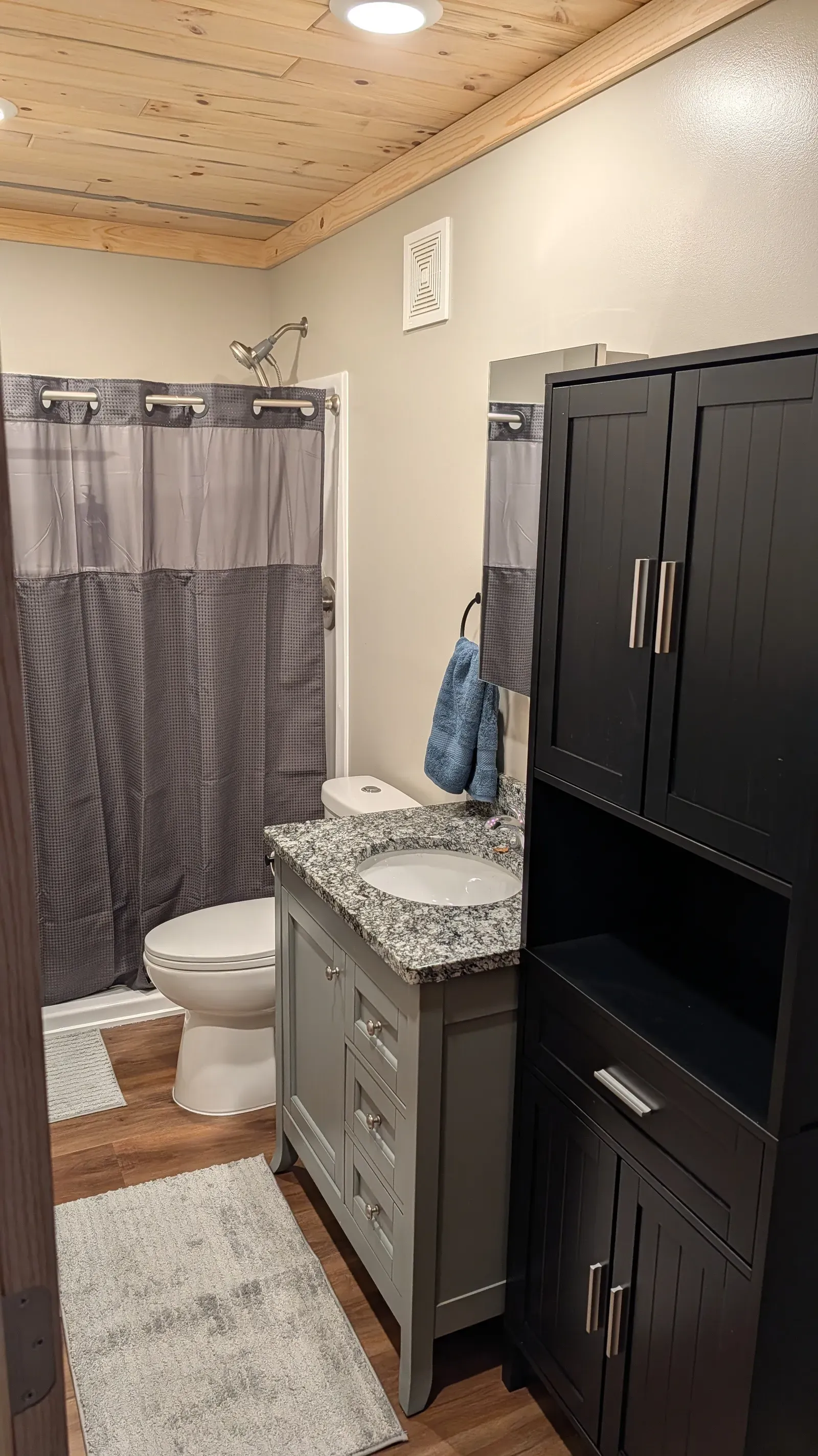 Original bathroom with blue tile walls, pine ceiling, and dated shower stall in Duluth, MN
