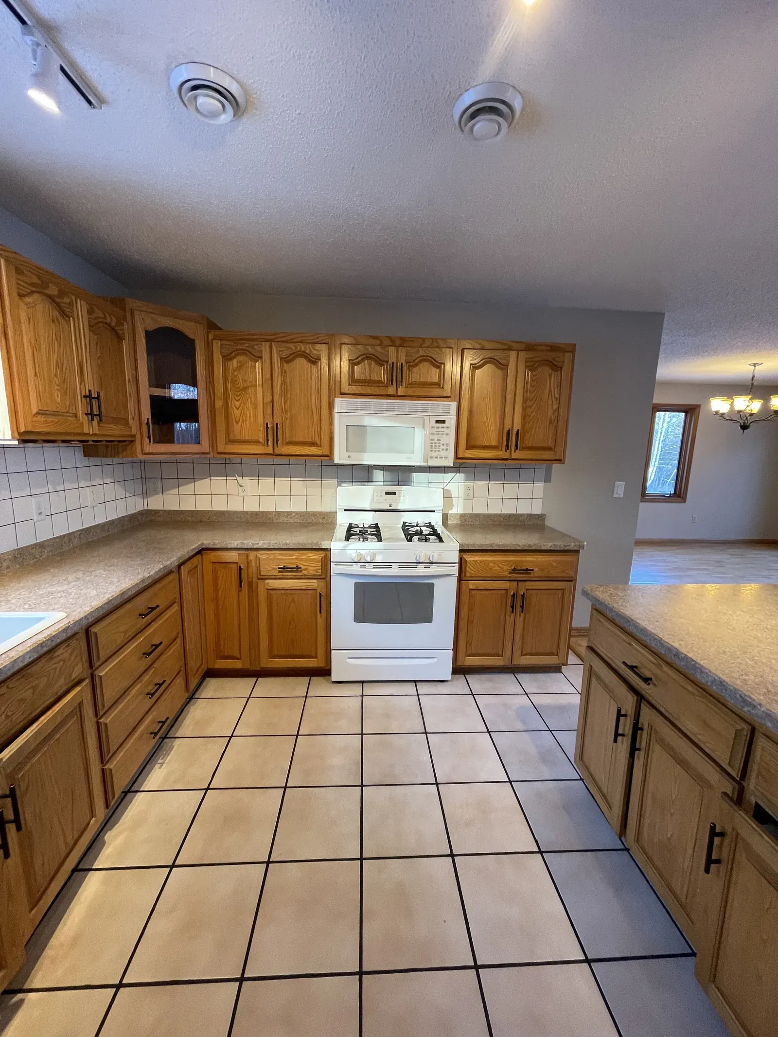 Dated Duluth kitchen with oak cabinets, white appliances, and ceramic tile floor