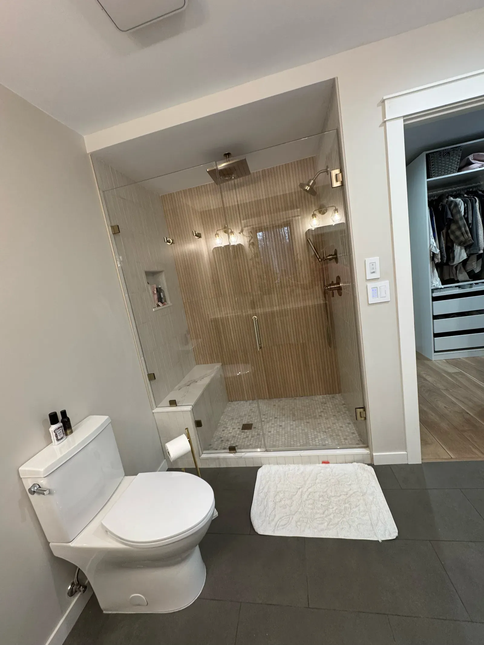 New walk-in shower with vertical tile, glass enclosure, and rain showerhead