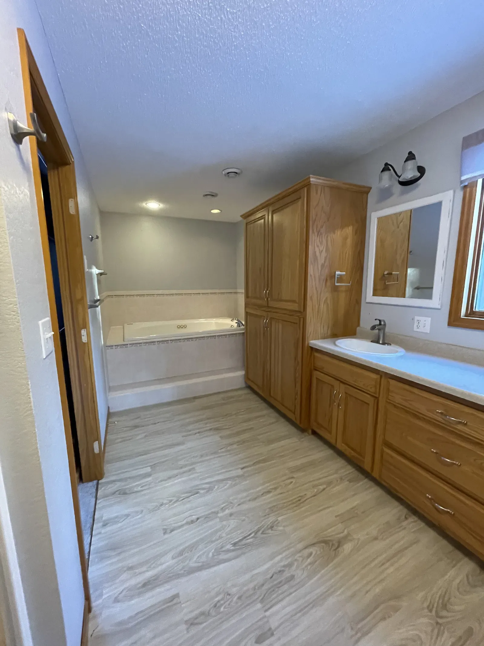 Original master bathroom showing oak cabinetry and jetted tub