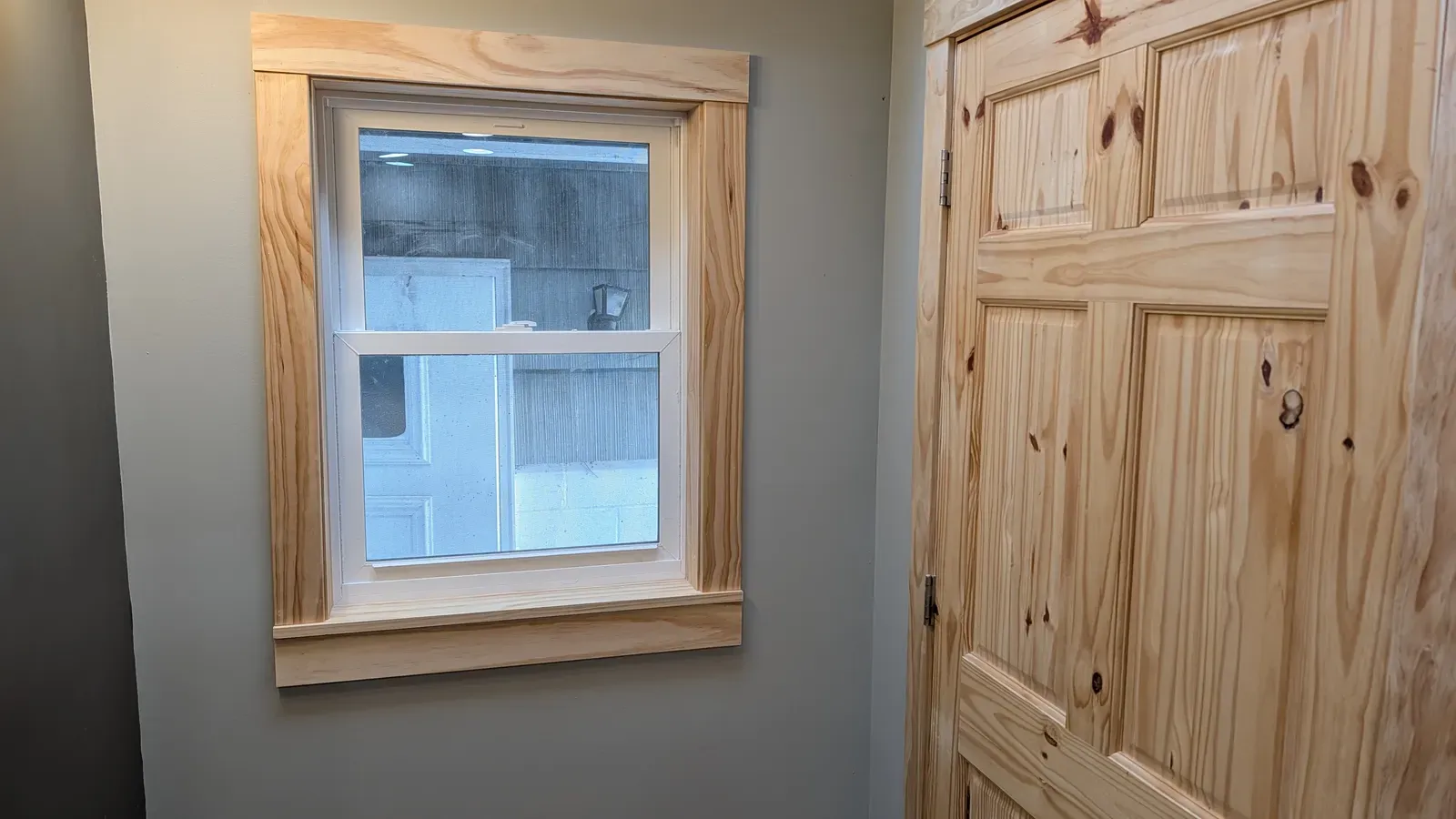 Finished window with custom knotty pine trim and matching pine door