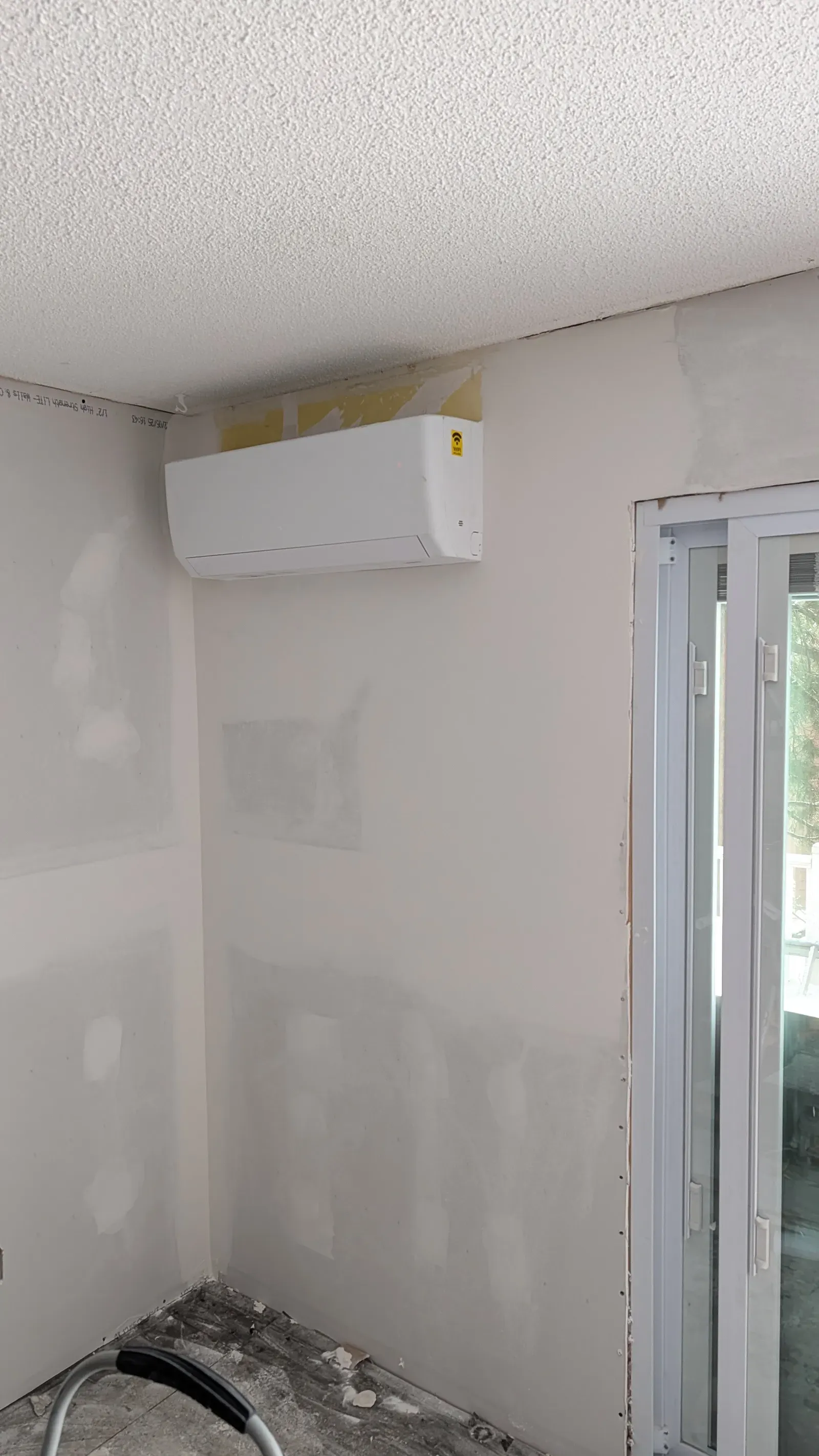 In-progress drywall with mini-split installed, mudding and taping visible